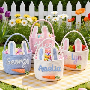 May include: Four Easter baskets in blue, pink, and white, each with bunny ears and a name embroidered on the front. The baskets are filled with colorful eggs and treats, and sit on a yellow and white checkered blanket.
