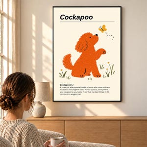 Puede incluir: Una lámina de arte mural enmarcada que muestra un perro Cockapoo naranja texturizado mirando hacia una mariposa amarilla. El diseño incluye el texto Cockapoo y una definición bajo la ilustración, sobre un fondo crema con flores verdes.
