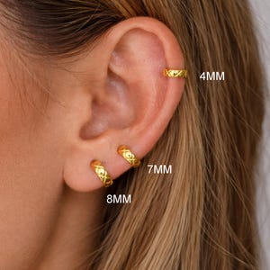 May include: Gold-coloured hoop earrings with a textured crisscross pattern. The image shows three different sizes: 4mm, 7mm, and 8mm. The earrings are displayed on an ear, showcasing their design and fit.