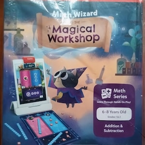 Può includere: Un gioco educativo in scatola intitolato "Math Wizard and the Magical Workshop". La scatola presenta un gatto dei cartoni animati in costume da mago, un iPad e un tabellone di gioco. Il gioco è per bambini dai 6 agli 8 anni e si concentra sull'addizione e la sottrazione.