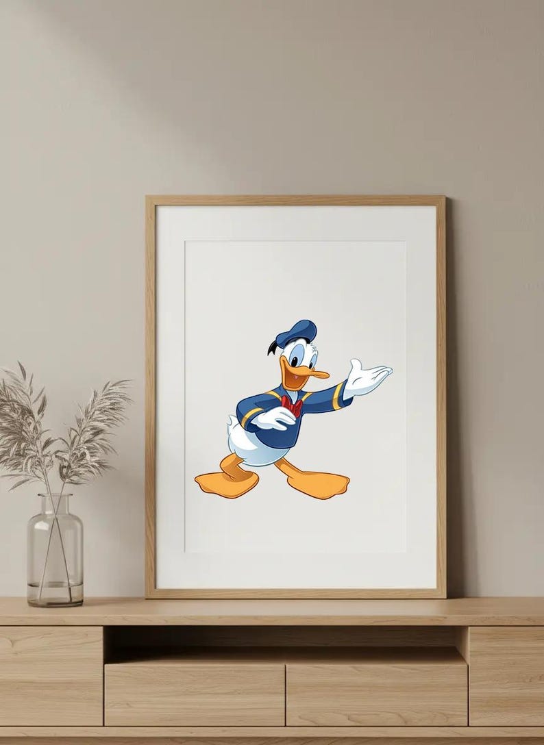 Puede incluir: Impresi&oacute;n enmarcada con una ilustraci&oacute;n de dibujos animados de Pato Donald. El personaje lleva su traje de marinero, con chaqueta y gorro azules y pajarita roja. La obra de arte est&aacute; sobre un fondo blanco dentro de un marco de madera.