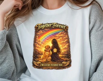May include: White t-shirt with a graphic featuring a woman and a golden retriever dog embracing under a rainbow. The text "Together Forever" and "I'm lucky to have you" are displayed on the shirt. The design has a warm, sunset color palette.