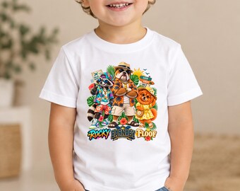May include: A white short-sleeve t-shirt featuring a colorful graphic of a raccoon, a bulldog, and a small dog dressed in tropical vacation attire. The graphic includes the text Rocky, Barnaby, and Floof, surrounded by palm leaves and flowers.