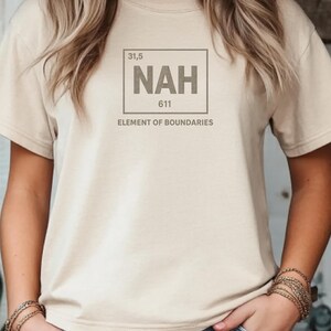 May include: A beige t-shirt featuring a graphic design. The design includes the word "NAH" in a box, with the numbers "31,5" and "611" above and below. Below the box, the text reads "ELEMENT OF BOUNDARIES".