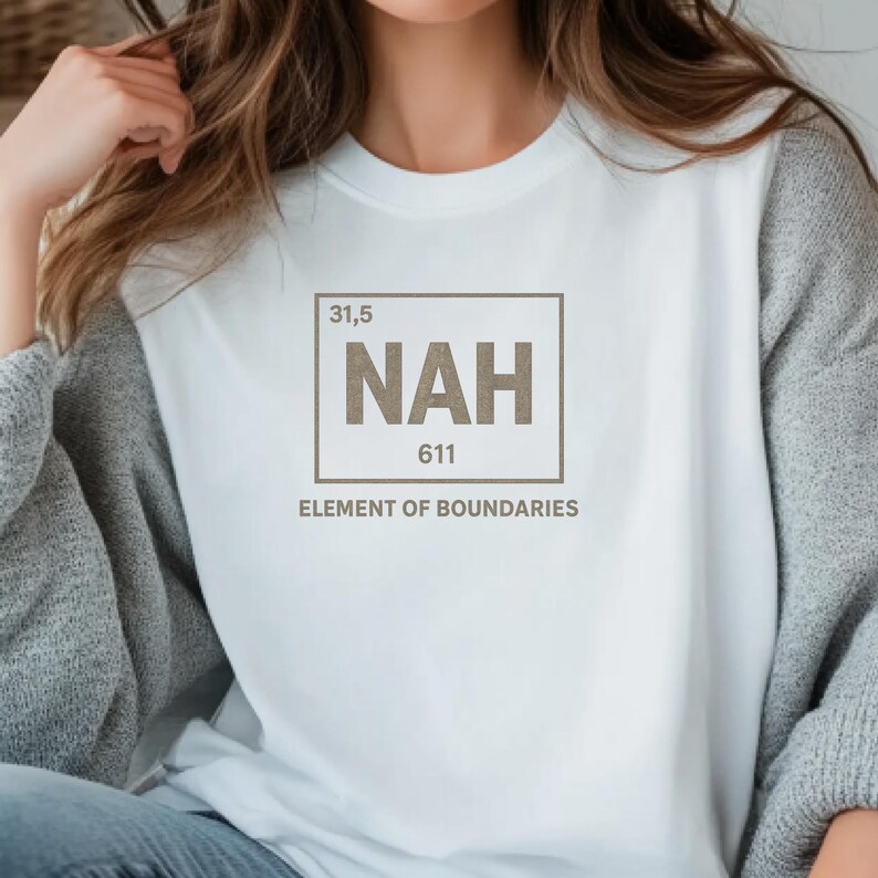 May include: White long-sleeve shirt with the text "NAH" in a box, resembling a periodic table element. Below the box, the text reads "ELEMENT OF BOUNDARIES". The shirt is a casual style.