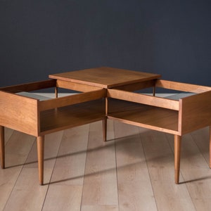 May include: A mid-century modern style coffee table with a square top and two rectangular side tables. The table is made of light brown wood and has tapered legs. The dimensions are approximately 30 inches long, 30 inches wide, and 18 inches high.