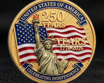 Puede incluir: Una moneda conmemorativa dorada que presenta la Estatua de la Libertad sosteniendo una antorcha. El fondo muestra una bandera estadounidense con el texto UNITED STATES OF AMERICA, 250 YEARS, 1776-2026 y CELEBRATING INDEPENDENCE en azul y oro.