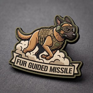 May include: A tactical morale patch featuring a tan Belgian Malinois dog wearing a military vest, headset, and goggles. The dog is running through a cloud of dust. Below the dog is a banner with the text FUR GUIDED MISSILE in black letters.