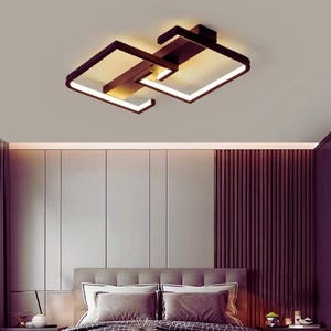 May include: Contemporary ceiling light fitting with a geometric design. The fixture has two square frames connected by a central structure, with warm white lighting. The frame is dark brown, creating a contrast with the light.