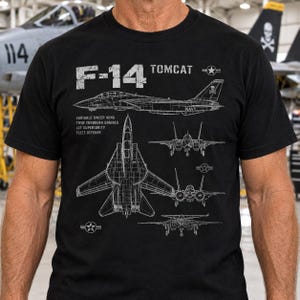 May include: A black t-shirt featuring a white technical blueprint graphic of the F-14 Tomcat fighter jet. The design includes side, top, and front views of the aircraft, along with the text F-14 TOMCAT, VARIABLE SWEEP WING, TWIN TURBOFAN ENGINES, AIR SUPERIORITY, and FLEET DEFENSE.