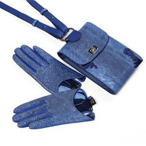Puede incluir: Un conjunto compuesto por un bolso bandolera azul texturizado con cierre de metal plateado y un par de guantes azules texturizados a juego. El bolso cuenta con una correa larga ajustable y los guantes tienen una peque&ntilde;a etiqueta negra con texto en blanco.
