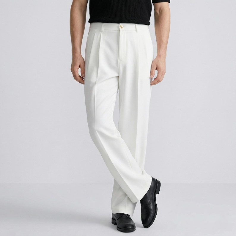 Pu&ograve; includere: Un pantalone bianco a pieghe con vita alta e gamba larga, abbinato a scarpe in pelle nera. La persona indossa anche una maglietta nera a maniche corte.