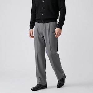Pu&ograve; includere: Una persona indossa un cardigan nero e pantaloni grigi a pieghe. I pantaloni sono di colore grigio unito e hanno una vestibilit&agrave; classica e su misura. La persona indossa anche scarpe di pelle nere.
