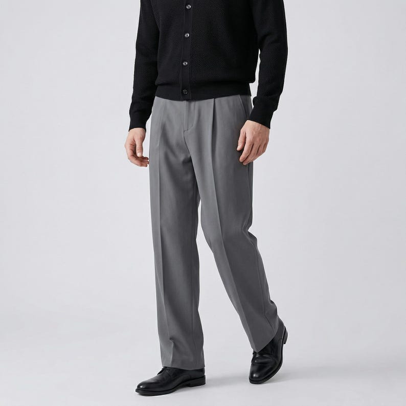Pu&ograve; includere: Una persona indossa un cardigan nero e pantaloni grigi a pieghe. I pantaloni sono di colore grigio unito e hanno una vestibilit&agrave; classica e su misura. La persona indossa anche scarpe di pelle nere.