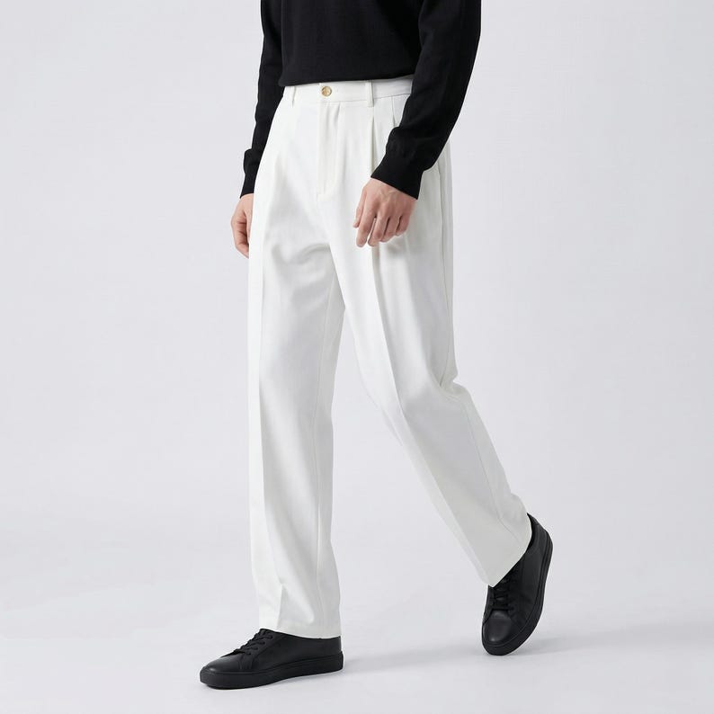 Pu&ograve; includere: Pantaloni bianchi a pieghe con chiusura a bottone, abbinati a una maglia nera a maniche lunghe e scarpe da ginnastica nere. I pantaloni hanno una vestibilit&agrave; ampia. L'outfit &egrave; adatto a occasioni casual o semi-formali.