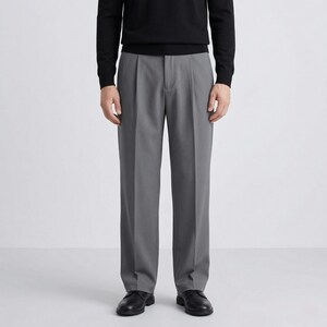 Pu&ograve; includere: Una persona indossa un maglione nero a maniche lunghe e pantaloni grigi a pieghe. I pantaloni hanno un design a gamba dritta e sono abbinati a scarpe in pelle nera. L'outfit &egrave; uno stile classico e minimalista.