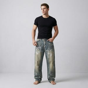 May include: A person wearing a black crew neck t-shirt and light blue denim jeans with white paint splatters and writing. The jeans have a relaxed fit.
