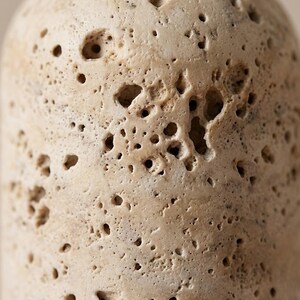 Puede incluir: Primer plano de una superficie de piedra beige y porosa. La piedra tiene numerosos agujeros irregulares y una textura rugosa. El color es un tono c&aacute;lido y neutro, con variaciones de sombra en la superficie. La apariencia general sugiere un material natural y desgastado.