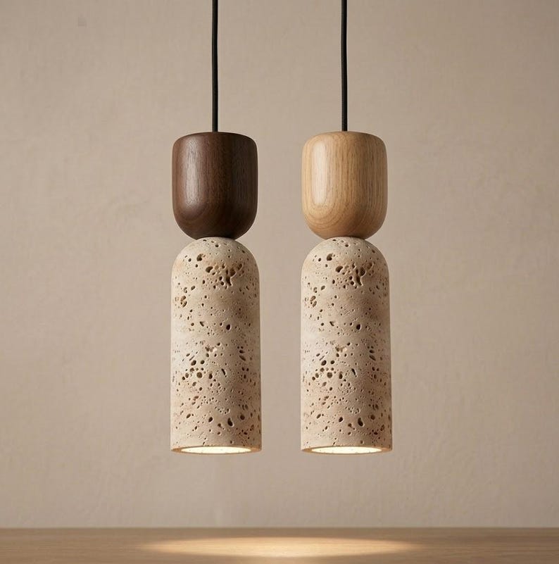 Puede incluir: Dos l&aacute;mparas colgantes modernas. Una tiene una parte superior de madera marr&oacute;n oscuro, la otra de madera clara. Ambas tienen una base cil&iacute;ndrica de piedra beige porosa. Las luces cuelgan de cables negros.
