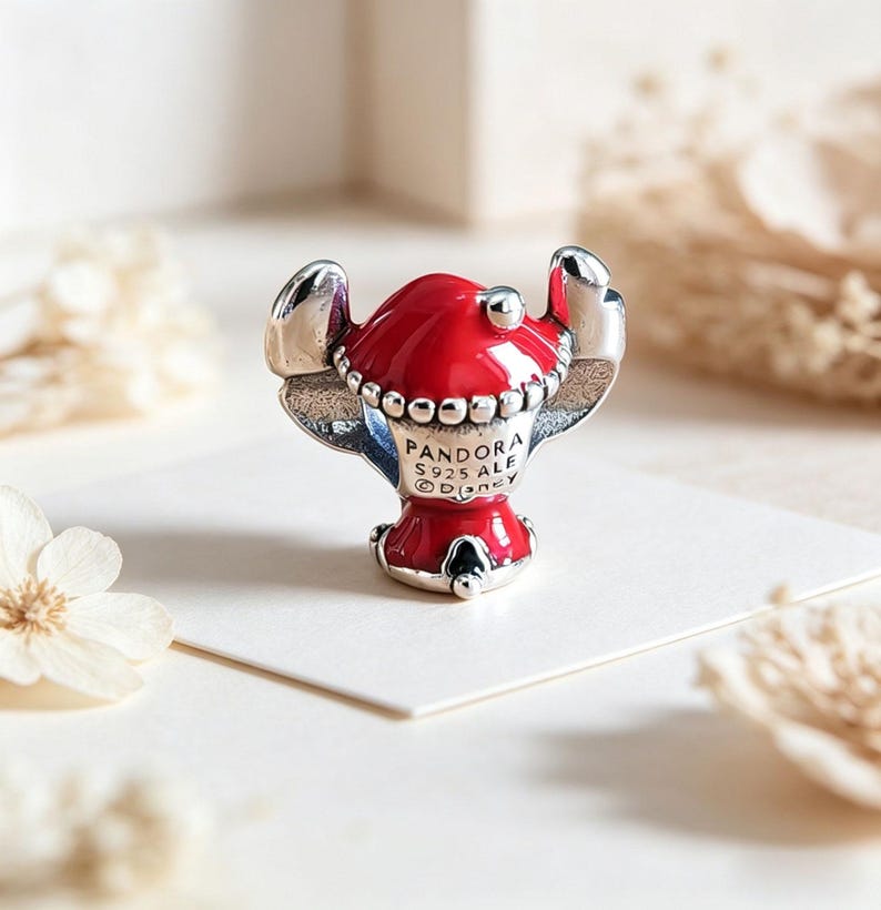 Op de afbeelding: Een Pandora-bedel met een rood en zilver karakterontwerp. De bedel heeft een rode kop en lichaam met zilveren details, inclusief de oren. De bedel is gemarkeerd met "Pandora S925 ALE Disney".
