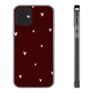 Könnte beinhalten: Eine weinrote Handyhülle mit einem Muster aus kleinen, weißen Herzen. Die Hülle hat einen transparenten Rand und einen Kameraausschnitt. Die Handyhülle ist für ein Smartphone konzipiert.