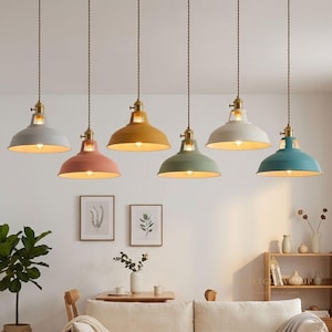 Puede incluir: Una colección de seis lámparas colgantes en varios colores, incluyendo gris, rosa, amarillo, verde, blanco y turquesa. Cada lámpara tiene una pantalla de metal y un accesorio de color latón. Las lámparas están suspendidas del techo por un cable marrón.