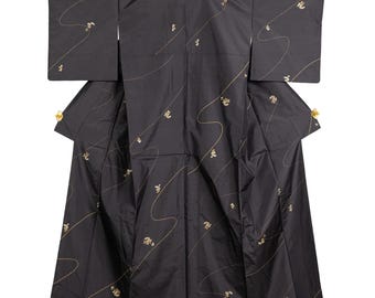 May include: A black kimono featuring long, wide sleeves and a pattern of thin, flowing gold lines interspersed with small, scattered gold floral motifs. The garment is displayed flat, showcasing its full length, structured collar, and wide cut.