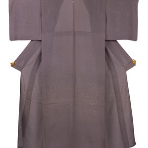May include: A gray kimono with a subtle dotted pattern and gold accents. The traditional Japanese garment features wide sleeves and a wrap-around design. The kimono is made of a soft fabric and has a simple, elegant style.