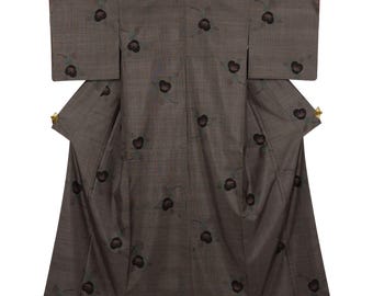 May include: A brown kimono with a floral pattern. The kimono features a repeating design of dark brown flowers with green accents. The garment is made of a textured fabric and has wide sleeves and a wrap-around design.