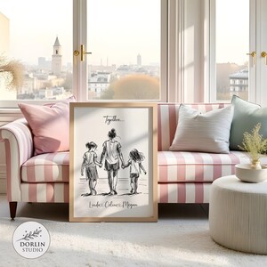 May include: A framed black and white sketch print featuring a mother and two children walking together, with the text "Together..." and names "Linda, Celine, Megan". The print is displayed on a white rug in front of a pink and white striped sofa.