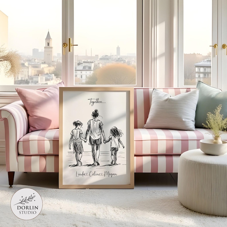 May include: A framed black and white sketch print featuring a mother and two children walking together, with the text "Together..." and names "Linda, Celine, Megan". The print is displayed on a white rug in front of a pink and white striped sofa.