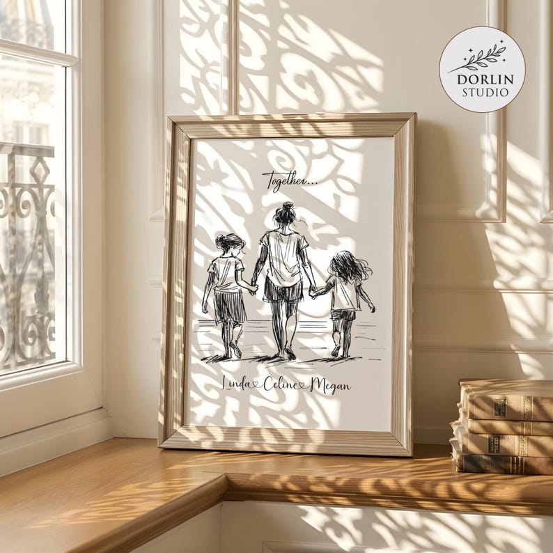 May include: A framed black and white sketch print depicting a mother and two children holding hands, with the word "Together..." above them. The names "Linda, Celine, Megan" are written below. The print is in a light wood frame.