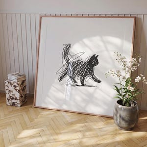 Puede incluir: Una impresión artística enmarcada con un boceto de gato negro. El gato está dibujado con un estilo garabateado, con una cola larga y una postura de caminar. La obra de arte está sobre un fondo blanco, enmarcada en un tono de madera clara.