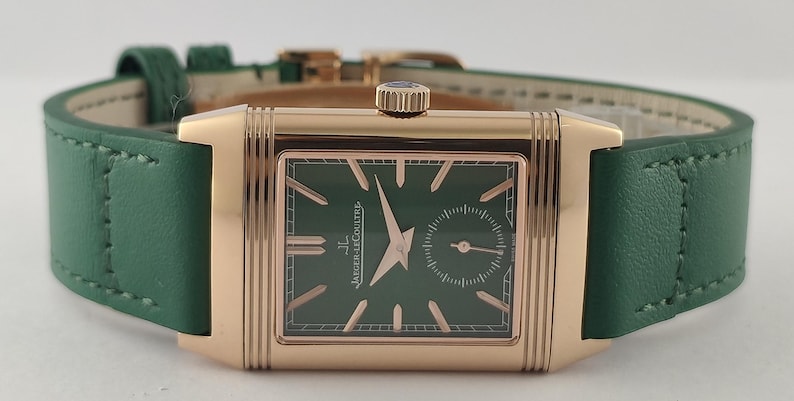 Puede incluir: Un reloj de pulsera rectangular con caja de oro rosa y esfera verde oscuro. El reloj presenta manecillas e &iacute;ndices en oro rosa, una subesfera de segundos y el texto Jaeger-LeCoultre. Est&aacute; sujeto a una correa de cuero verde lisa.