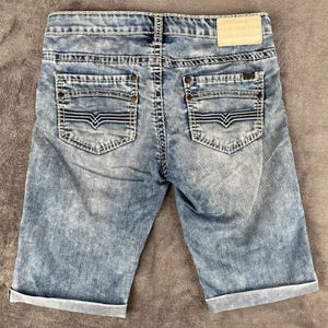 May include: A white ceramic mug with a black handle and the text "But first, coffee" in a handwritten style. The mug is on a white surface. The mug is approximately 4 inches tall.