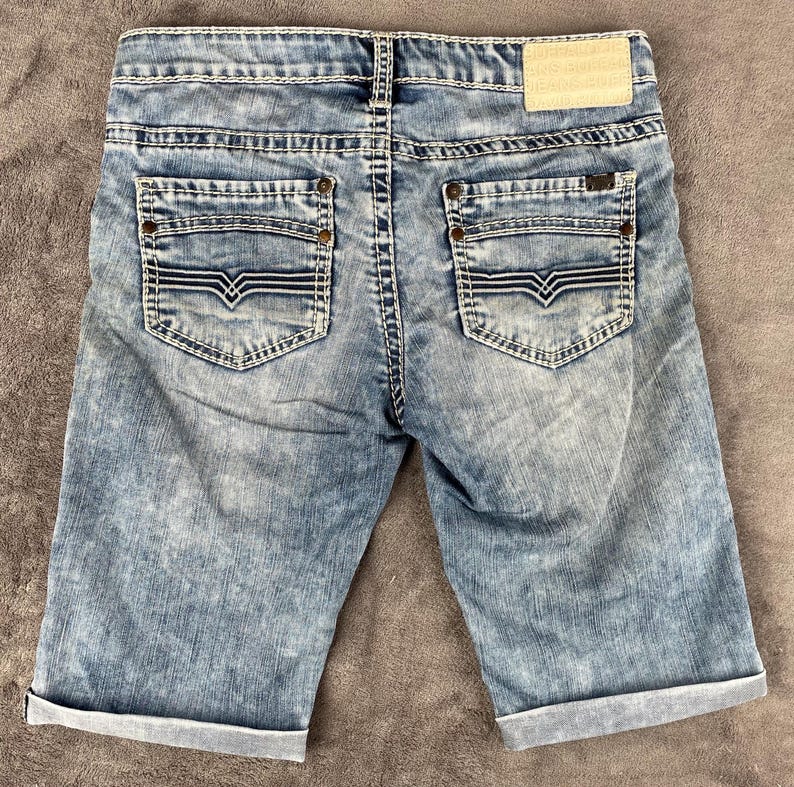 May include: A white ceramic mug with a black handle and the text "But first, coffee" in a handwritten style. The mug is on a white surface. The mug is approximately 4 inches tall.