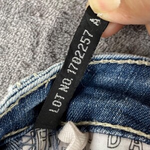 May include: A white ceramic mug with a black handle and the text "But First, Coffee" in a black, handwritten-style font. The mug is on a white surface.