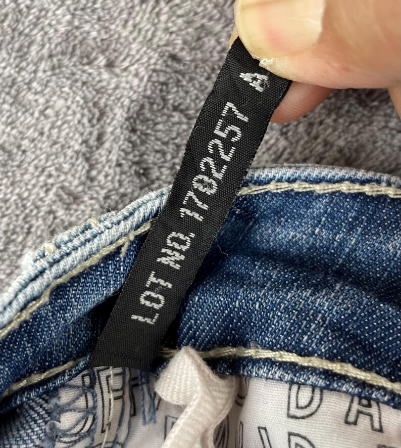 May include: A white ceramic mug with a black handle and the text "But First, Coffee" in a black, handwritten-style font. The mug is on a white surface.