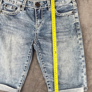 May include: A white ceramic mug with a black handle and the text "But First, Coffee" in a handwritten style. The mug is on a white surface. The mug is approximately 4 inches tall.