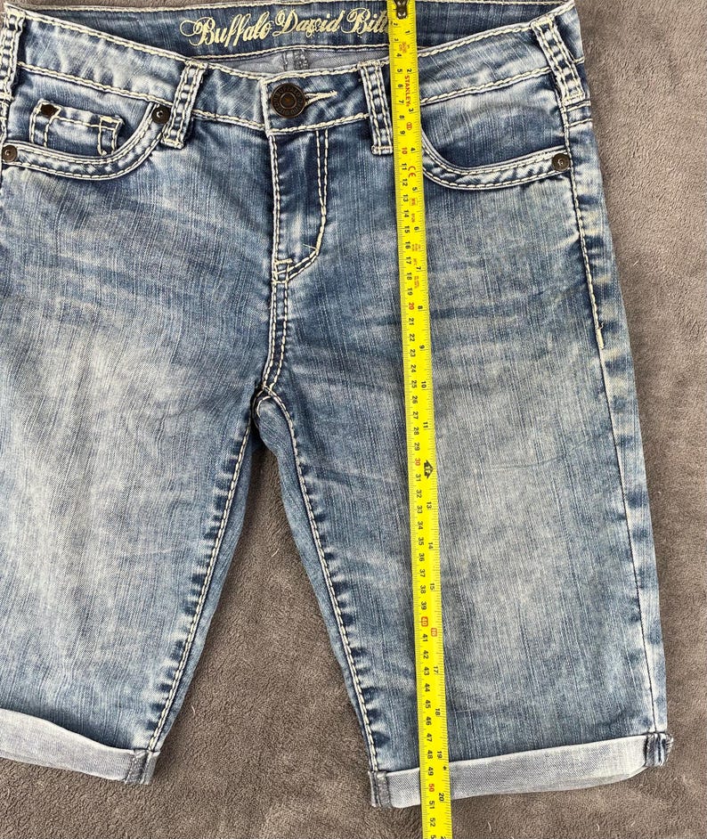 May include: A white ceramic mug with a black handle and the text "But First, Coffee" in a handwritten style. The mug is on a white surface. The mug is approximately 4 inches tall.
