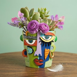 Könnte beinhalten: Eine weiße Keramik-Tasse mit schwarzem Henkel und dem Text "But First, Coffee" in schwarzer, fetter Schrift. Die Tasse steht auf einer Holzoberfläche. Die Tasse ist etwa 10 cm hoch.