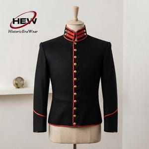 May include: A black military-style jacket featuring a high mandarin collar with red trim, a vertical row of gold-toned buttons down the front, and red piping accents along the collar, cuffs, and front closure, displayed on a mannequin torso.