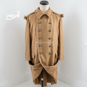 May include: A tan double-breasted coat with large silver buttons. The coat has a notched collar, shoulder epaulettes, and two front pockets. The coat is displayed on a mannequin. The text "HEW" and "HistoricEraWear" are visible.