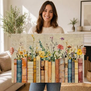 May include: A rectangular canvas print depicting a row of vintage books with colourful flowers and greenery emerging from the tops. The background is a faded dictionary page. The books are in shades of blue, orange, and brown.