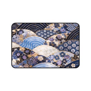 以下が含まれることがあります： 日本のデザインにインスパイアされた長方形のマウスパッド。青、白、金の色合いで、様式化された波と花のモチーフが特徴です。マウスパッドには黒い縁があります。
