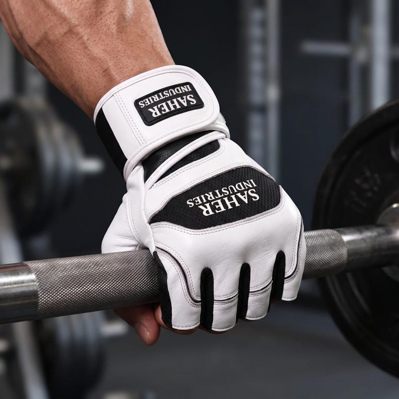 May include: A white and black fingerless weightlifting glove with a wrist strap featuring the text SAHER INDUSTRIES. The glove has a white leather-like exterior with black mesh panels and a black and white logo patch on the wrist and back of hand.