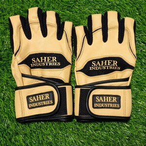 May include: A pair of fingerless gloves in tan and black. The gloves feature black mesh panels, tan leather sections, and adjustable wrist straps with hook-and-loop closures. The text SAHER INDUSTRIES is printed in gold on the back and wrist strap.