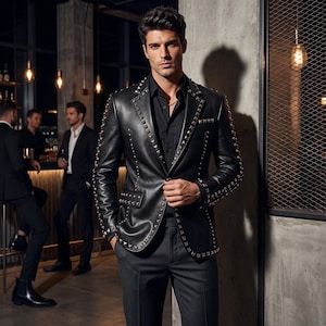 Peut inclure: Un blazer en cuir noir orné de clous pyramidaux argentés le long des revers, des rabats de poches et des manches. La veste est portée sur une chemise noire boutonnée et associée à un pantalon noir, offrant une allure structurée et formelle.