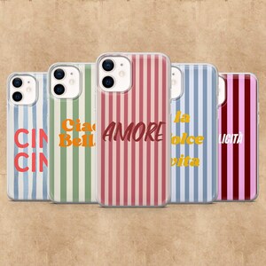 Op de afbeelding: Een verzameling telefoonhoesjes met verticale strepen in verschillende kleuren, waaronder blauw, groen, rood en roze. Elke hoes heeft een Italiaans woord of zin in een contrasterende kleur, zoals "AMORE" en "CIAO".