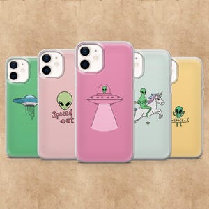 Può includere: Una collezione di custodie per telefoni con disegni a tema alieno. Le custodie presentano illustrazioni di UFO, alieni e un unicorno. Le custodie sono in vari colori, tra cui verde, rosa e giallo.